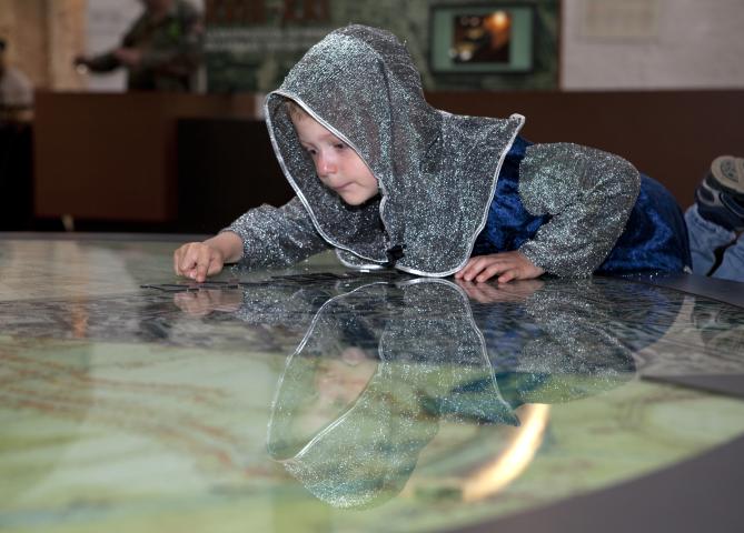 photo d'un enfant habillé en chevalier qui regarde un plan dans la Porte de Hal